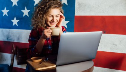 Pretty, happy woman using laptop while sitting at cafe. Young  woman sitting in a coffee shop and working on laptop.